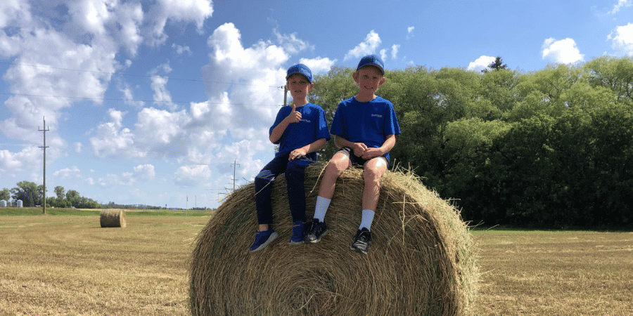2 kids sitting on an alfalfa round bale